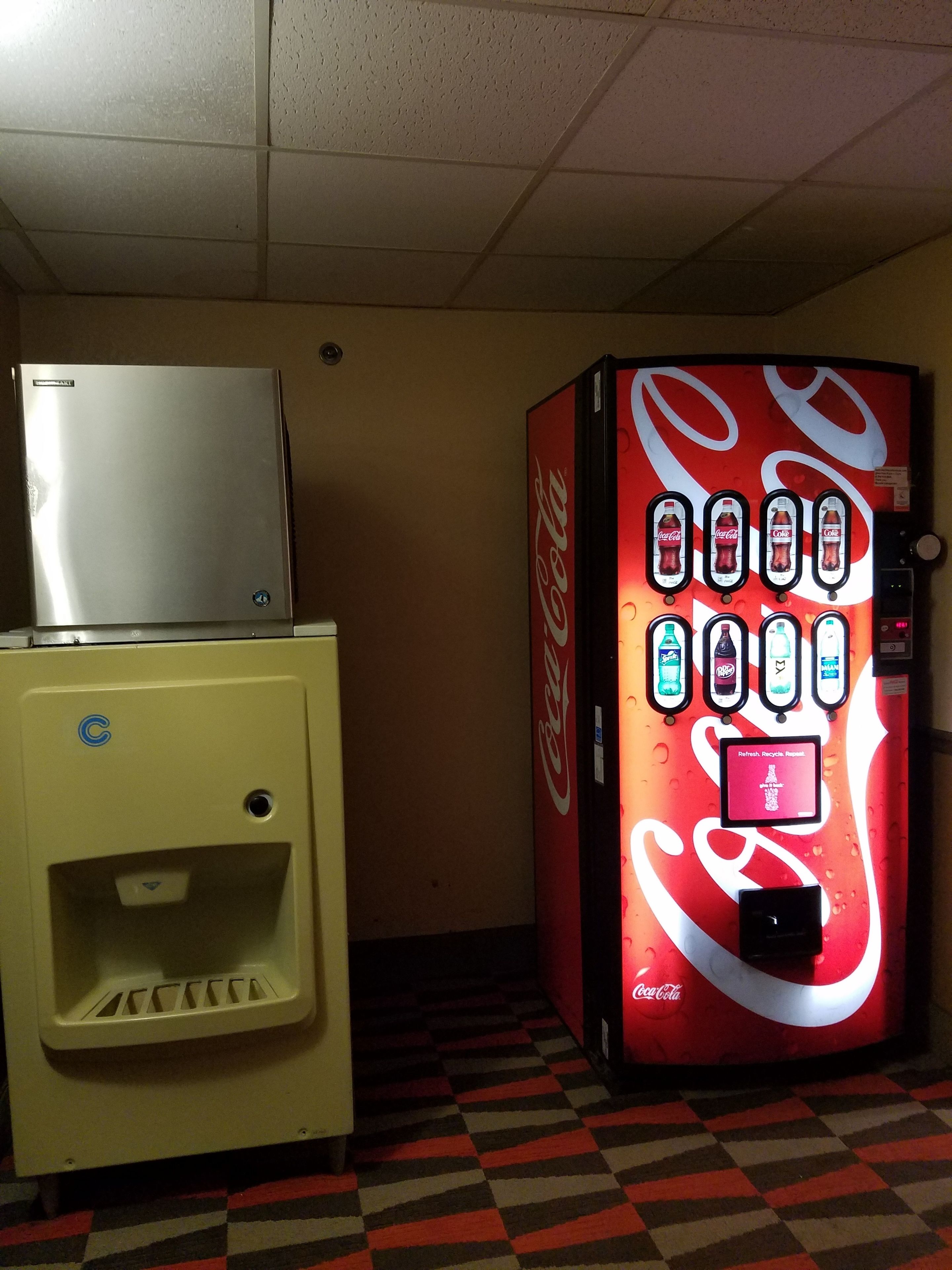 Una máquina expendedora y un refrigerador en una habitación con piso a cuadros.