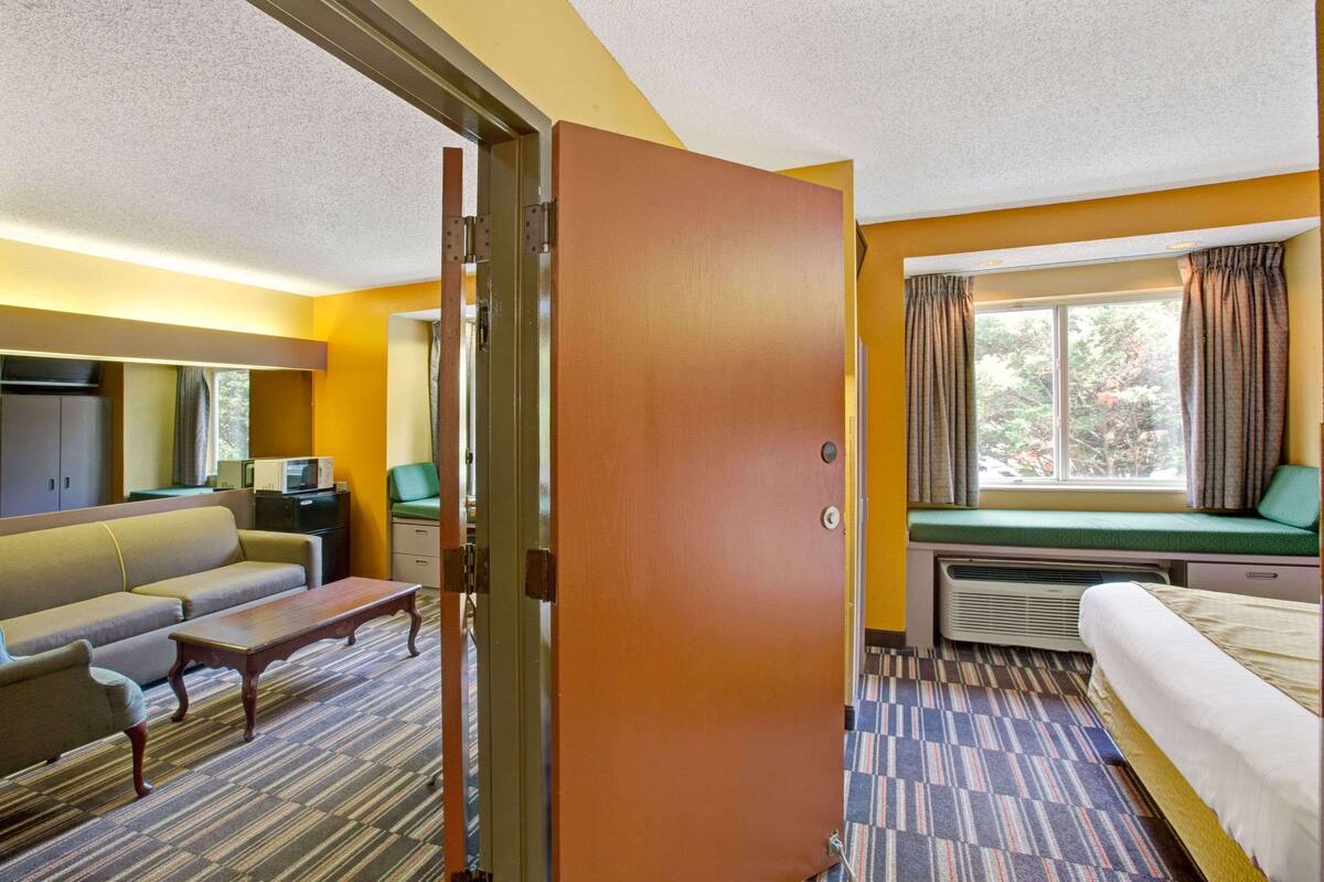 Habitación de hotel con sofá, una mesita, cama, ventana con cortinas y un radiador.