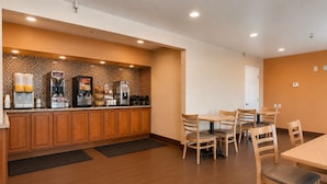 A modern kitchen with a breakfast bar, wooden cabinets, and a seating area with tables and chairs. - Vagabond Inn Bakersfield South (Bakersfield)