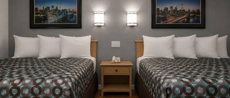 Habitación de hotel con dos camas, una mesita de noche y dos lámparas de pared.