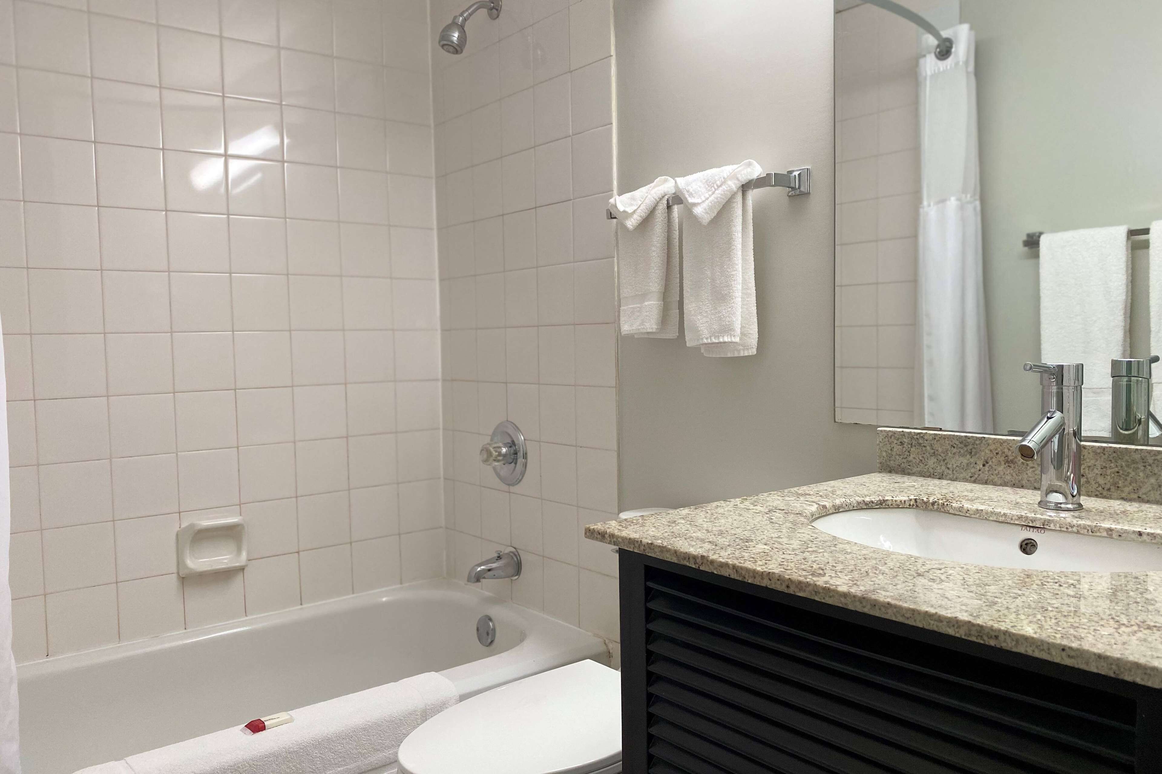 A bathroom with a bathtub, a toilet, a sink, and a mirror.