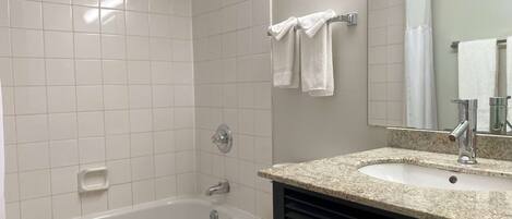 A bathroom with a bathtub, a toilet, a sink, and a mirror.