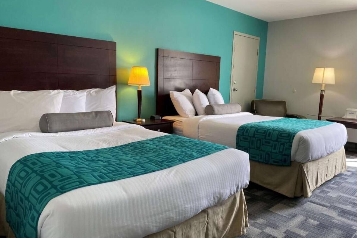 A hotel room with two beds, a desk, and a chair.