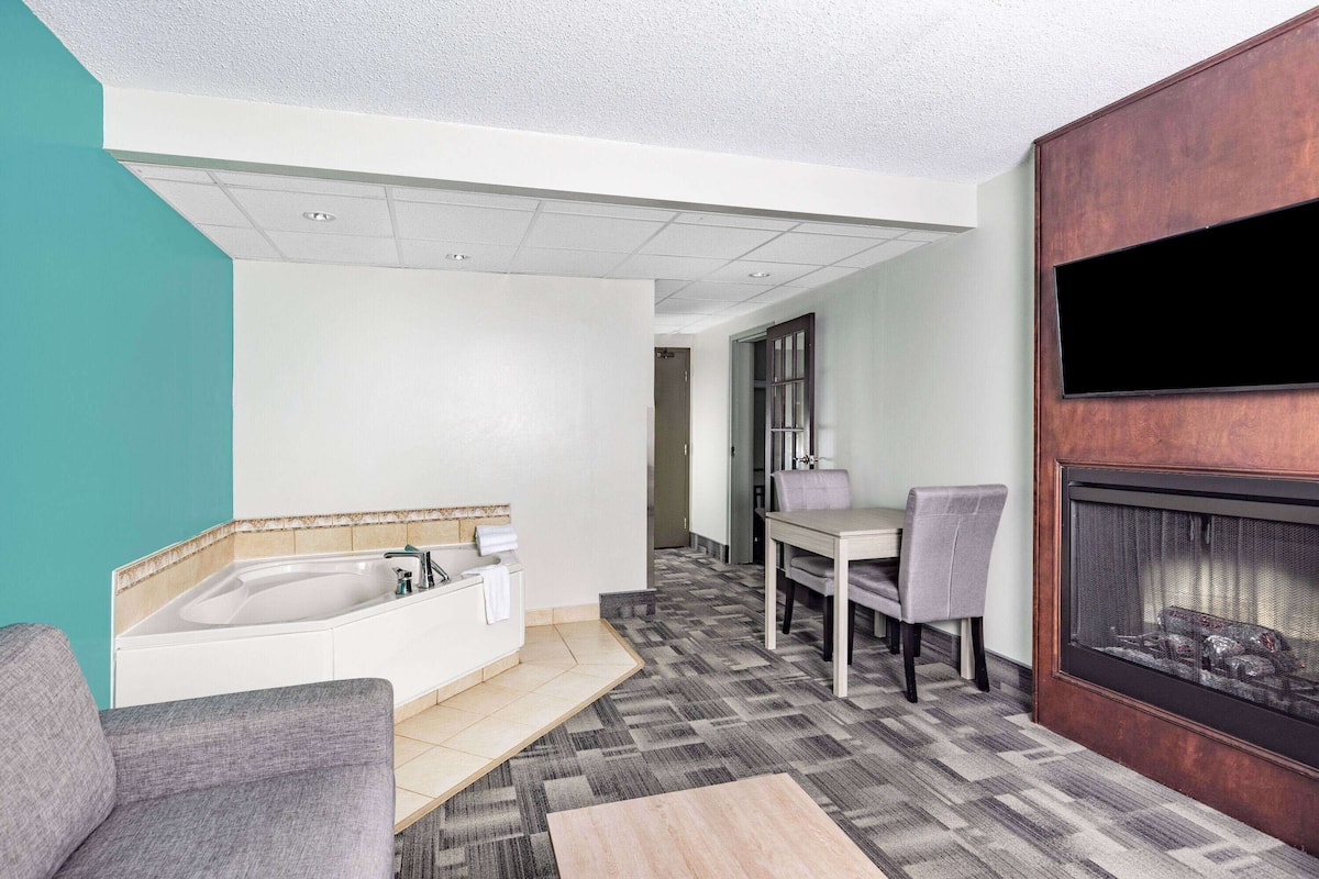 A modern bathroom with a bathtub, a sink, and a shower. There is a dining area with a table and chairs.