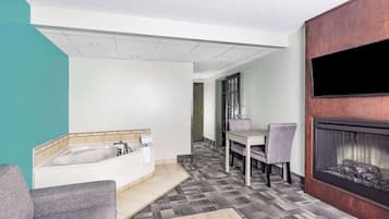 A modern bathroom with a bathtub, a sink, and a shower. There is a dining area with a table and chairs.
