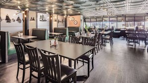 Un restaurante con cabinas y mesas, un techo alto con vigas a la vista y obras de arte en las paredes.