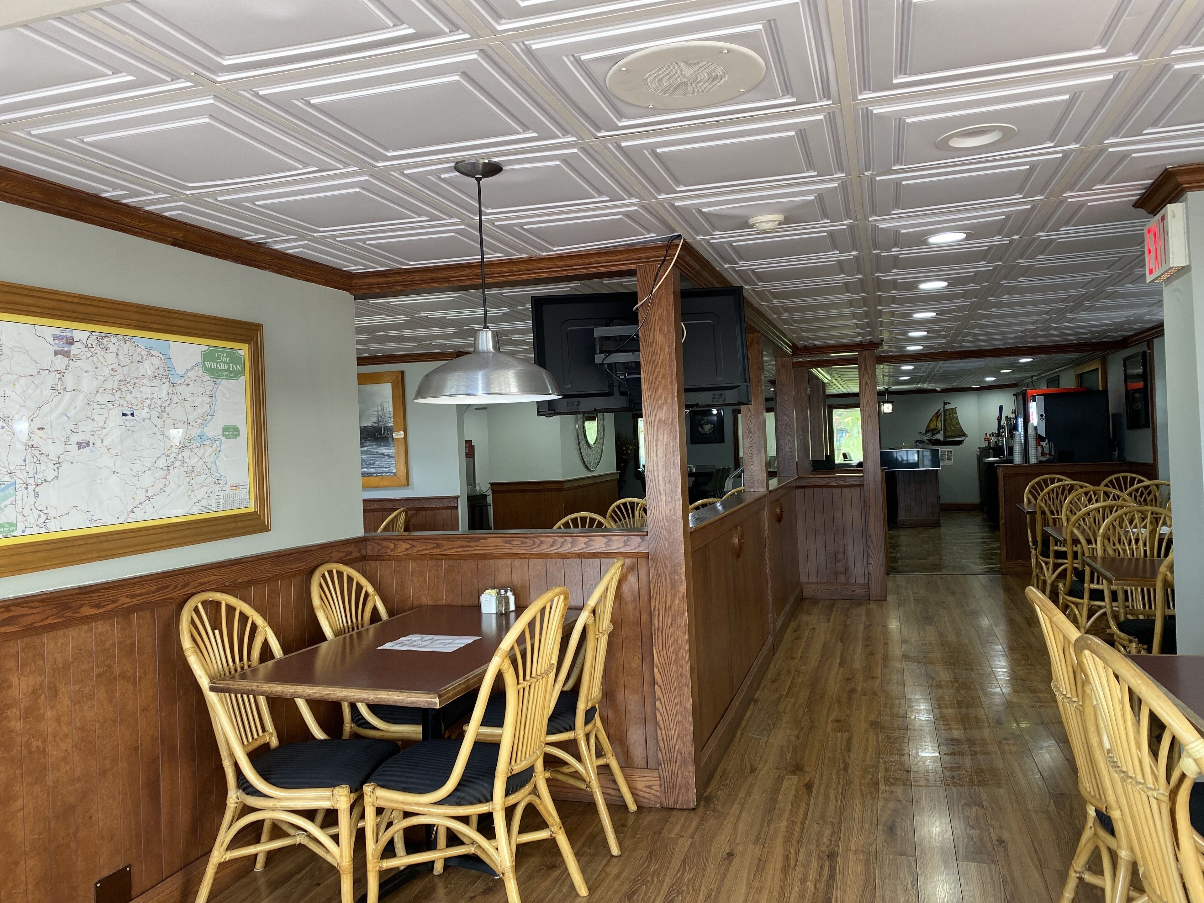 Um restaurante com painéis de madeira, um mapa na parede e um balcão comprido.