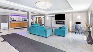 Un moderno vestíbulo de hotel con mostrador de recepción, zona de estar y una pantalla de televisión.