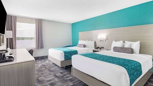 Habitación de hotel con dos camas, un escritorio y una ventana con cortinas.