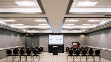 A conference room with a projector screen displaying "The Galt House Legendary Hotel Louisville" and a podium. Rows of chairs are arranged facing the screen.