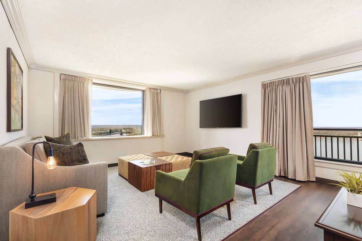 A modern living room with a sofa, two armchairs, a coffee table, and a TV mounted on the wall.
