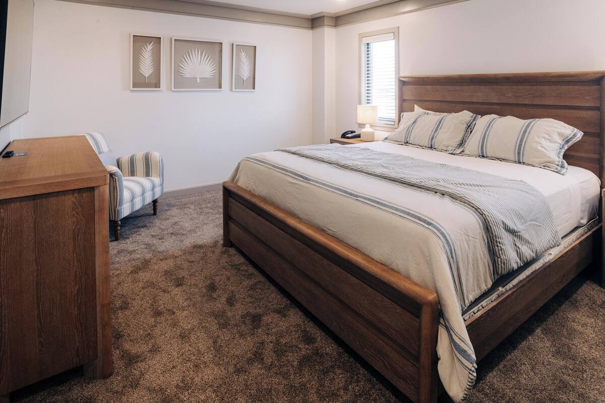 A bedroom with a wooden bed, a desk, a chair, and three wall-mounted art pieces.