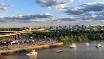 A riverside view with boats, a crowd, and a bridge.