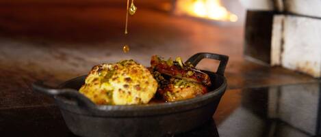 A cast iron skillet with food being drizzled with sauce.