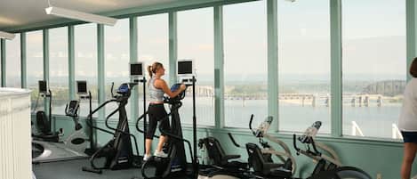 Ein Fitnessraum mit Cardiogeräten und Blick auf eine Brücke und Wasser.