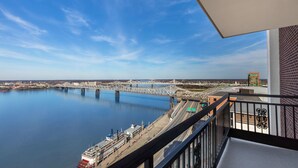 A balcony with a view of a river, a bridge, and a cityscape.