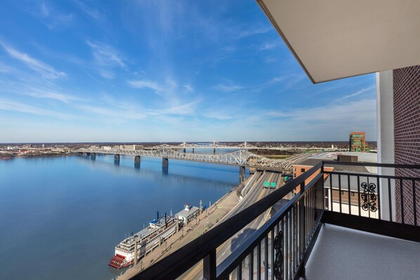 A balcony with a view of a river, a bridge, and a cityscape.