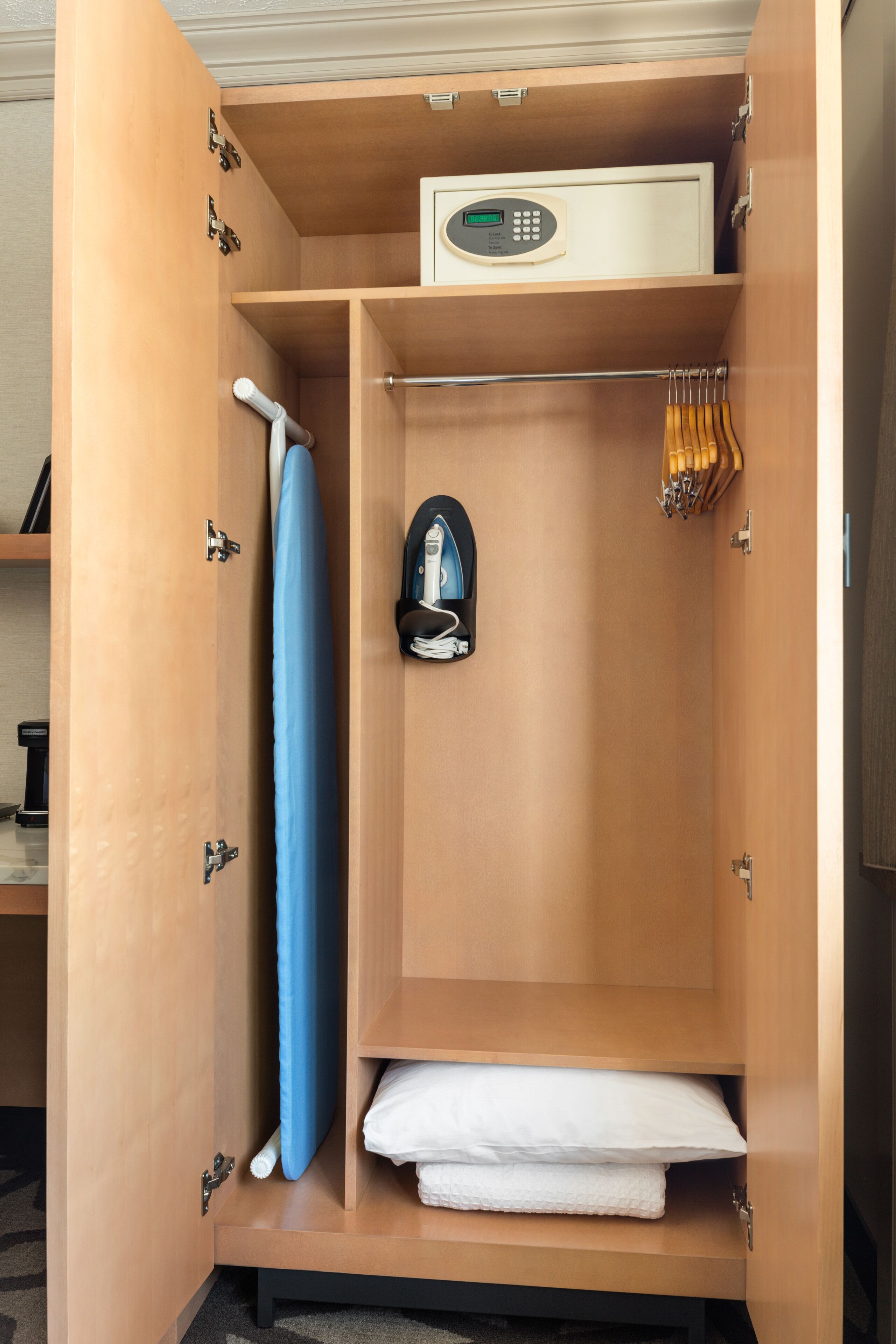 A wooden wardrobe with a control panel, a blue towel, and a white towel.