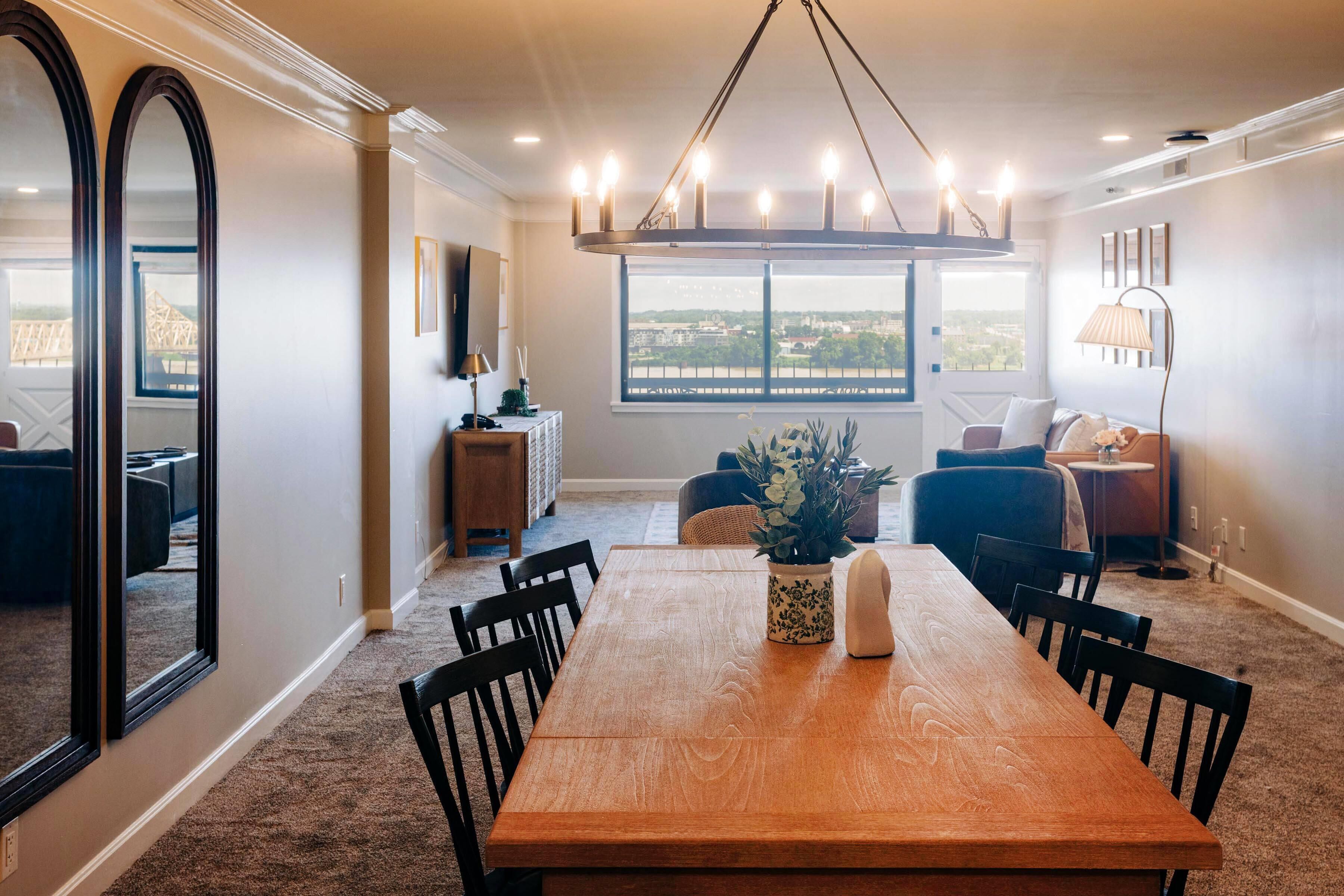 A dining area with a wooden table, chairs, and a view of the city through large windows.