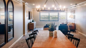 Un comedor con una mesa de madera, sillas y vistas a la ciudad a través de amplios ventanales.