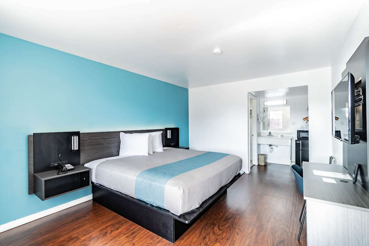 Una habitación de hotel moderna con una cama, mesita de noche y un escritorio con silla.