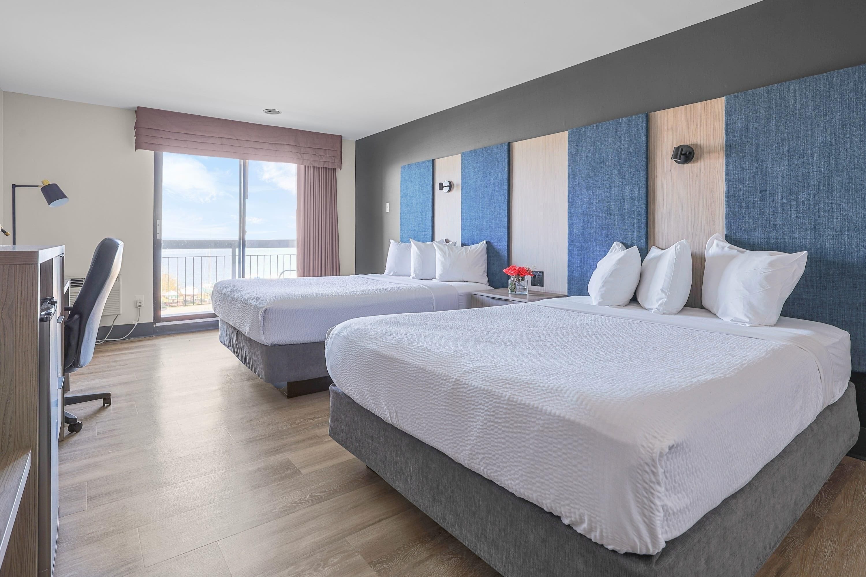 Ett hotellrum med två sängar, ett skrivbord och en stol.