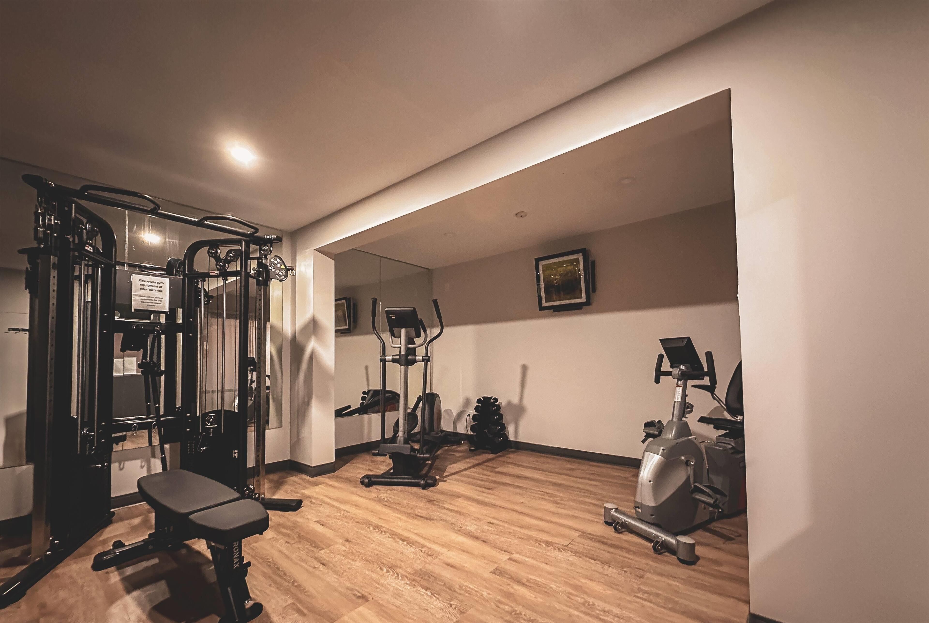 Une salle de sport équipée d’un banc, d’appareils d’exercice et d’un miroir.