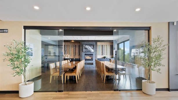 A modern interior with a glass partition, wooden flooring, and two potted plants. - The Jordan Ramada by Wyndham (Lincoln)