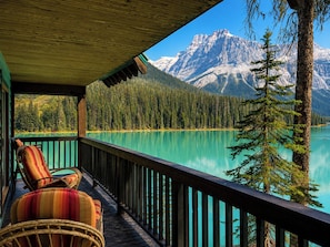 A wooden deck with a view of a turquoise lake and snow-capped mountains.