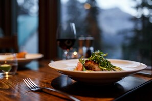 Una mesa con un plato de comida, una copa de vino y un tenedor.