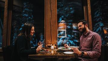 Deux personnes sont assises à une table, devant des verres à vin et des assiettes remplies de nourriture.