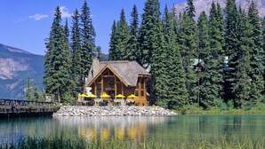 A lodge with a wooden exterior, situated on a lakeside with a mountain backdrop. - Emerald Lake Lodge (Field)
