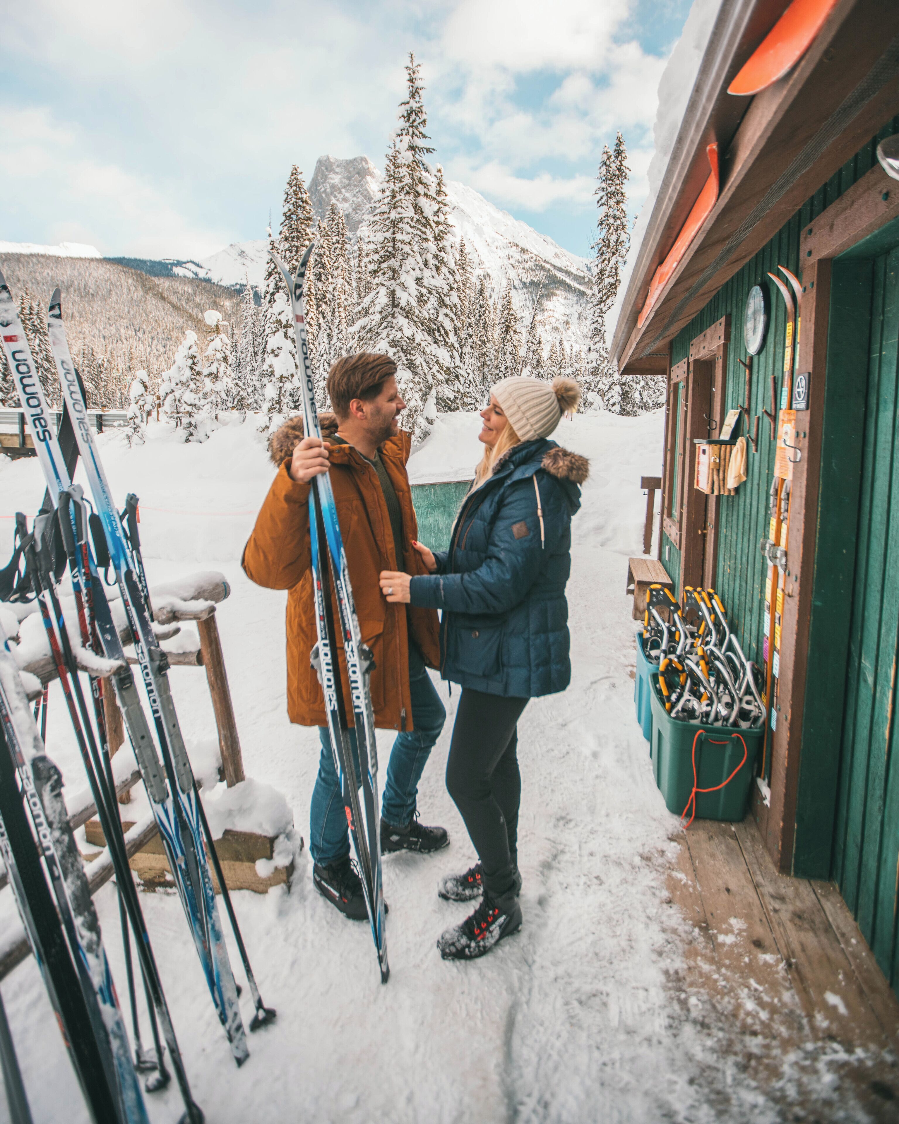A wooden building with ski equipment stored outside.