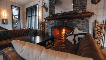 A cozy living room with a stone fireplace, leather sofas, and a large window.