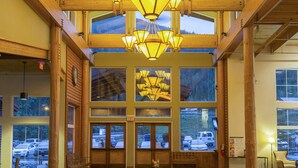 A spacious lobby with a large wooden ceiling, multiple windows, and a statue in the center.