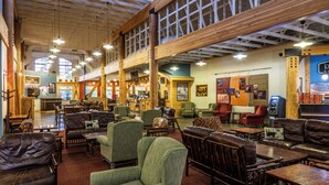 A spacious interior with high ceilings, wooden beams, and a variety of seating options including leather sofas and armchairs. - Denali Park Village (Denali National Park)