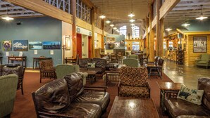 A spacious lobby with high ceilings, wooden beams, and a variety of seating options including leather sofas and patterned chairs. - Denali Park Village (Denali National Park)