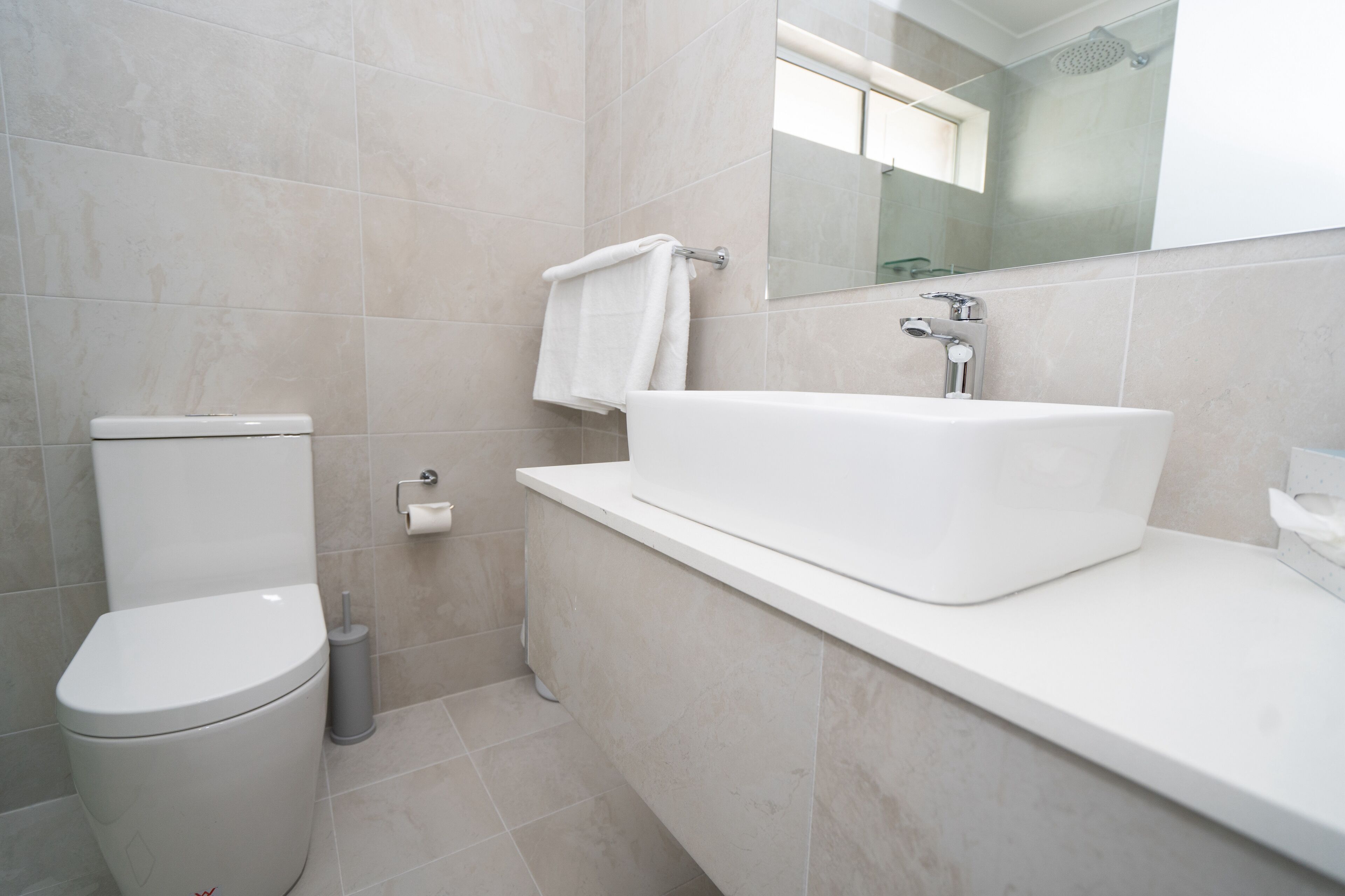 Un baño moderno con inodoro, lavamanos y espejo.