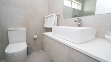 Un baño moderno con inodoro, lavamanos y espejo.