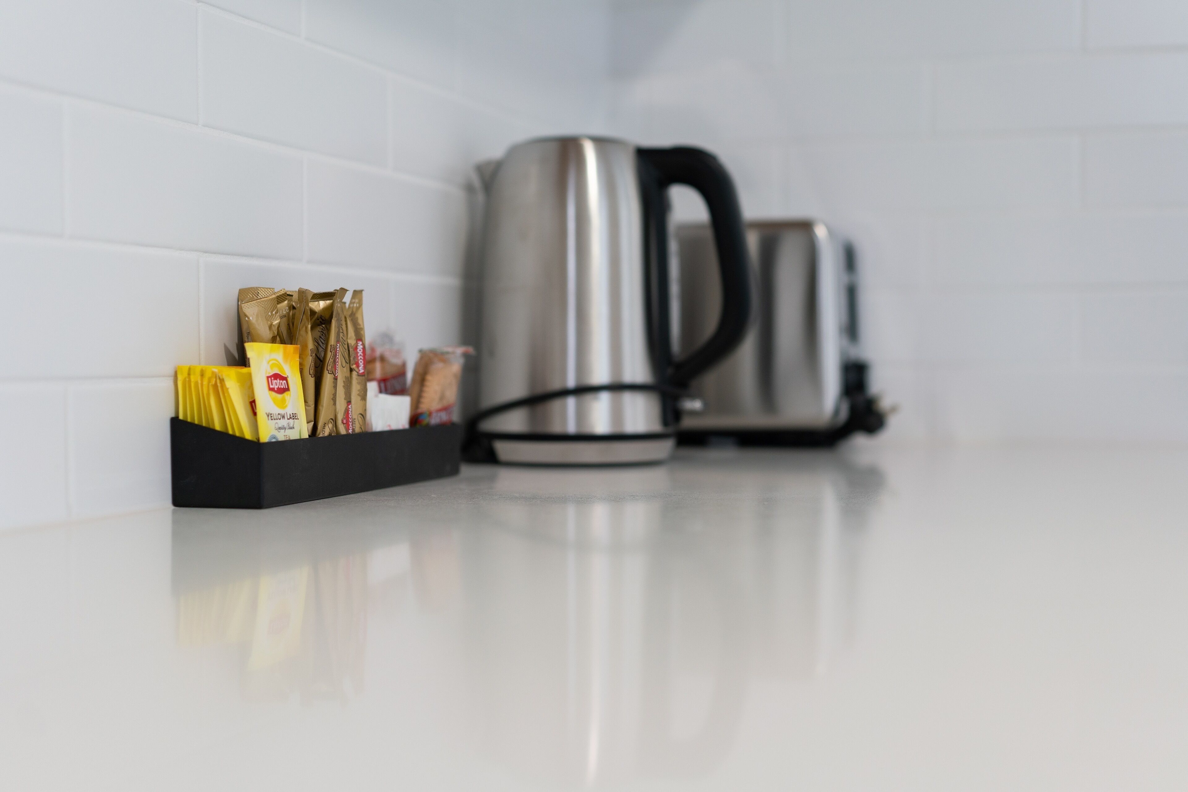 Un piano di lavoro della cucina con un bollitore in acciaio inossidabile e una scatola nera contenente diversi alimenti.