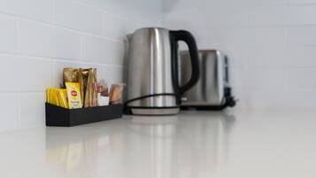Un piano di lavoro della cucina con un bollitore in acciaio inossidabile e una scatola nera contenente diversi alimenti.