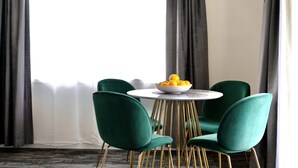 A dining area with a round table, four green chairs, and a bowl of fruit. - Littomore Suites Bathurst (Bathurst)