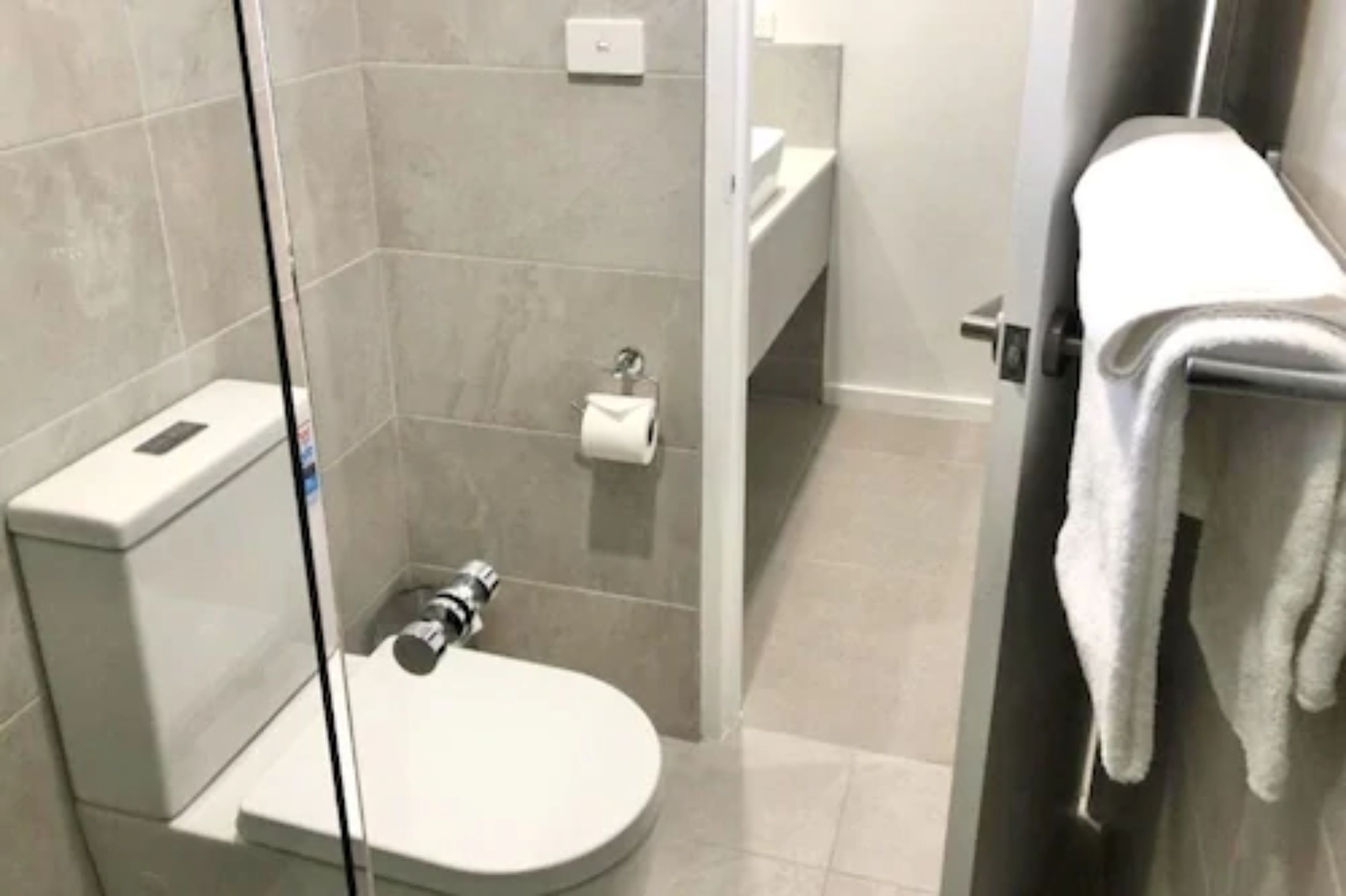 Une salle de bain moderne équipée de toilettes, d’une douche et d’un porte-serviettes.