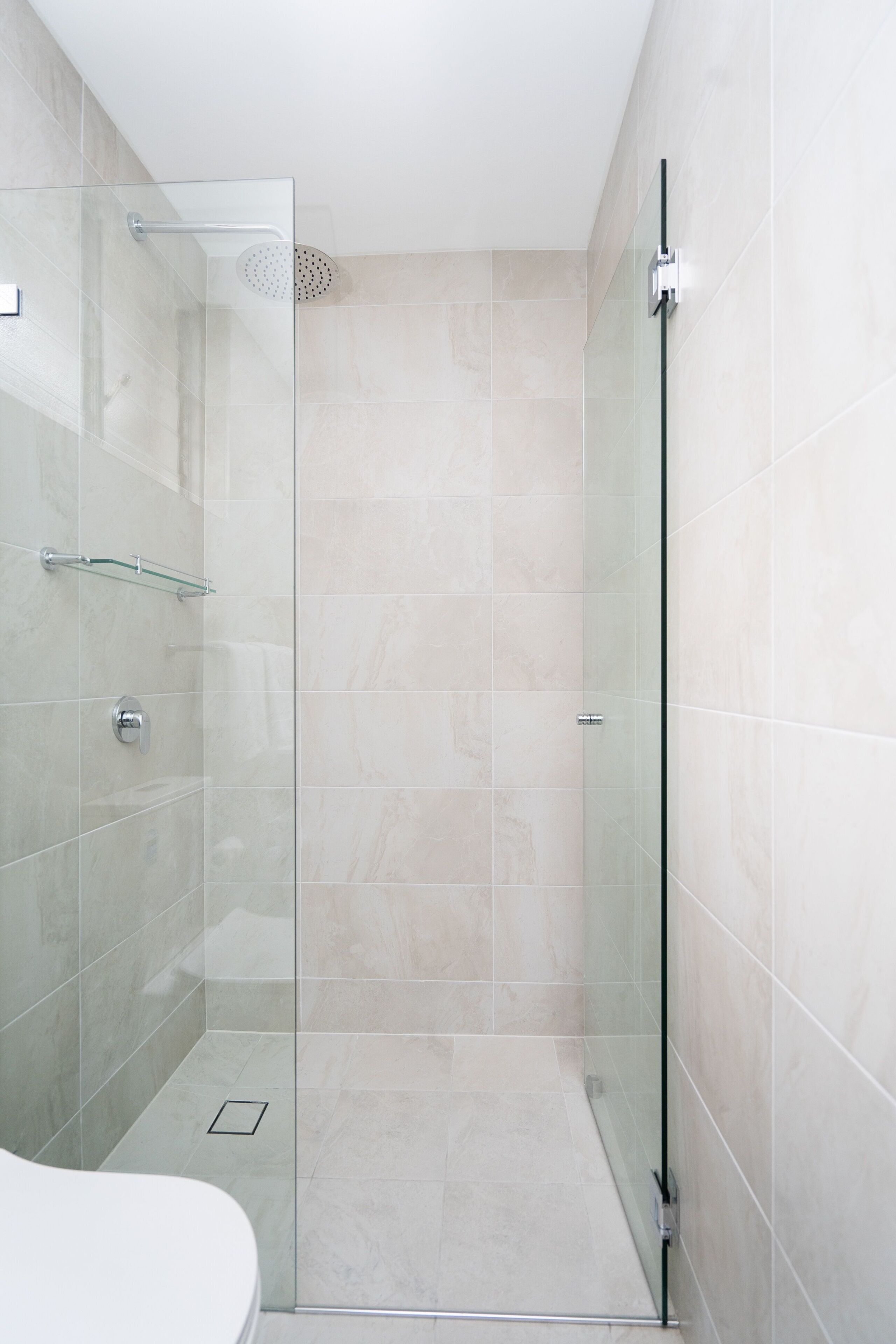 A modern bathroom with a glass shower enclosure, a glass door, and a white toilet.
