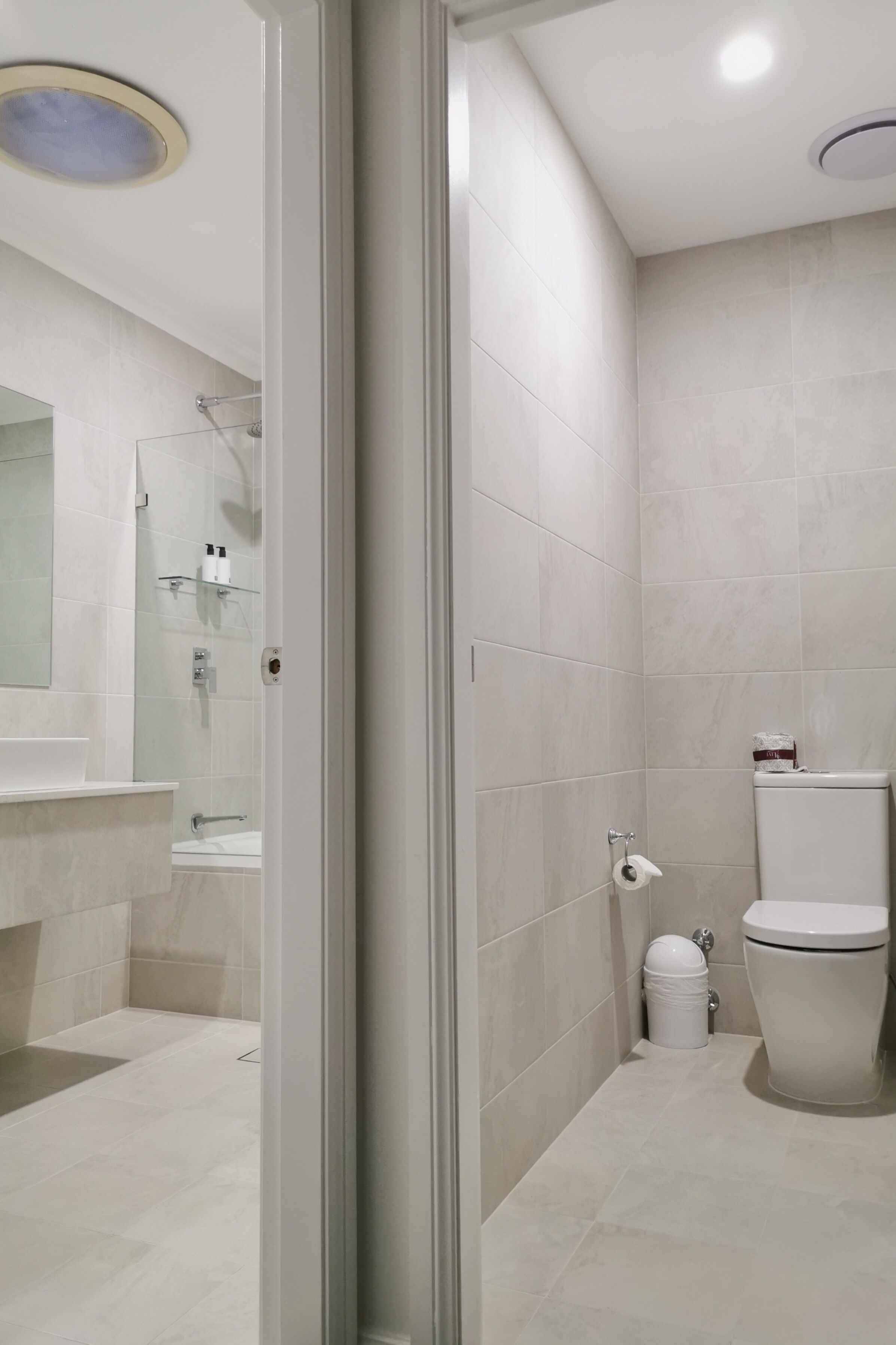 Une salle de bain moderne avec une douche à parois de verre, des toilettes et un lavabo surmonté d’un miroir.