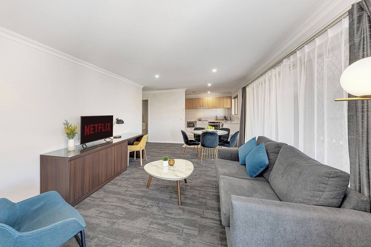 A modern living room with a grey sofa, a coffee table, and a TV displaying 'NETFLIX'.