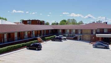 A motel with multiple units, a parking lot, and a clear blue sky.