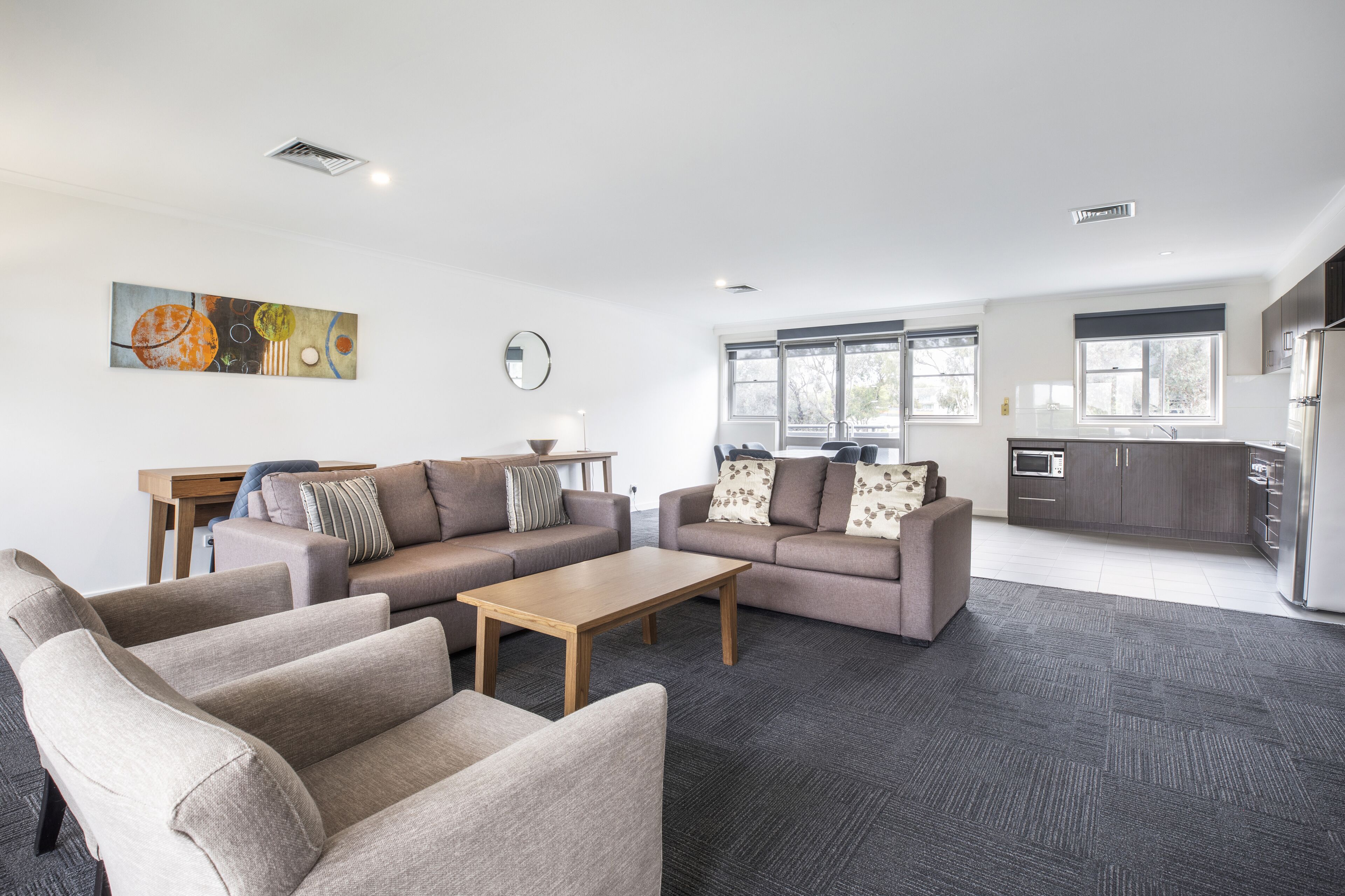 A modern living room with two sofas, a coffee table, and a dining area with a table and chairs.