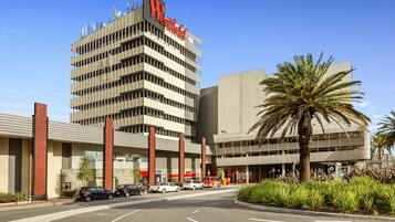 Een hotel met een opvallend 'Westfield'-bord, een parkeerplaats en een palmboom.