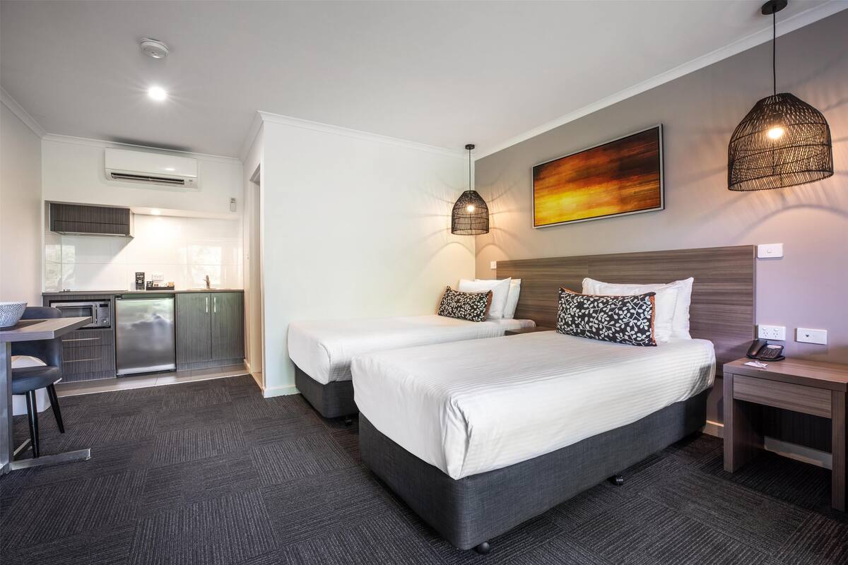 Ein Hotelzimmer mit zwei Betten, einer Küchenzeile und einem Essbereich.